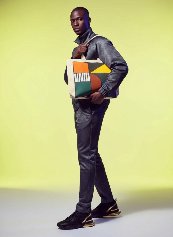 Man holding a colorful tote bag against a yellow background